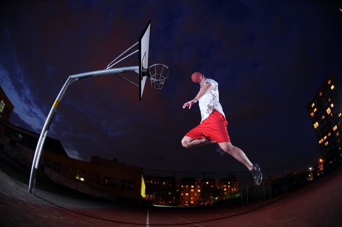 Man jumps for a basketball shot at night