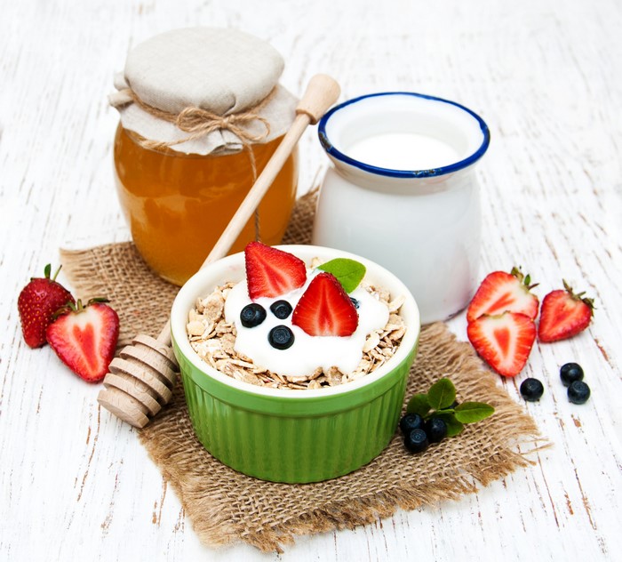 Muesli with yogurt, strawberries, blueberries, honey, and milk