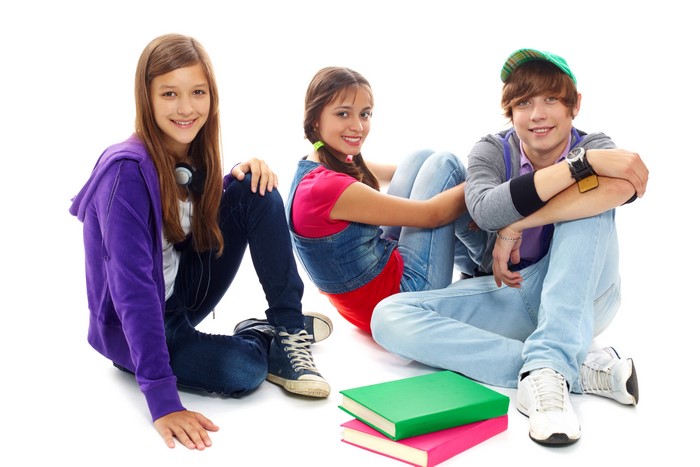 Three teenagers sitting with books on white background