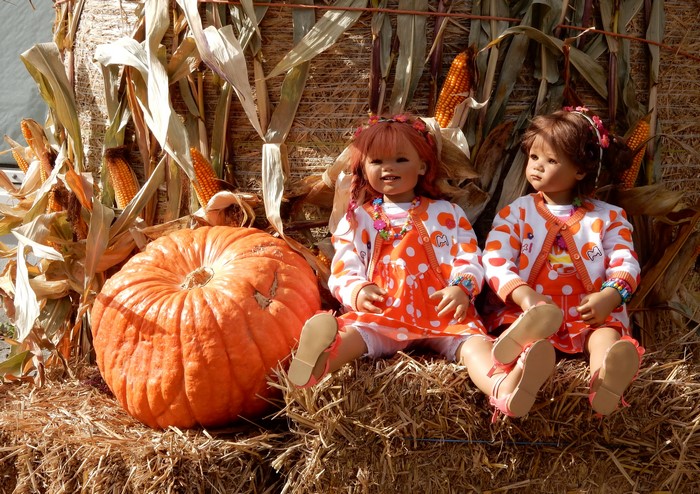 Two dolls with pumpkin and corn display
