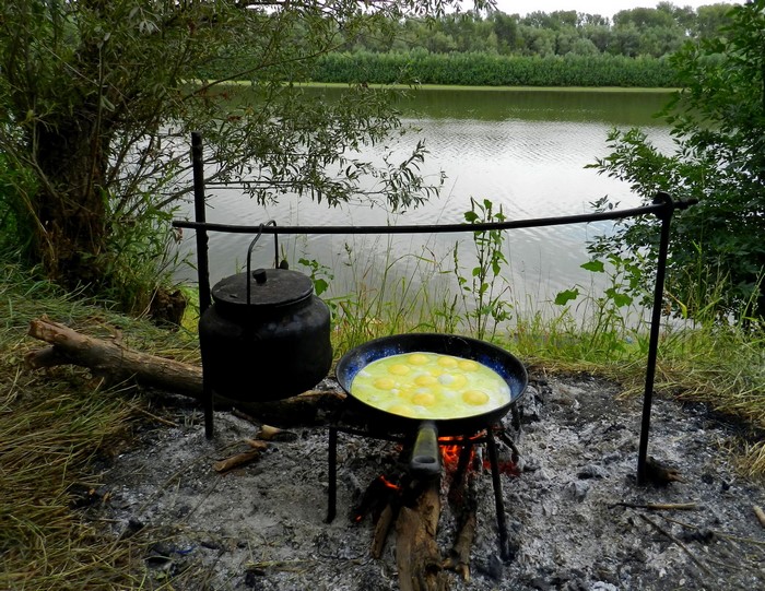 Cooking eggs and water over a bonfire by a river