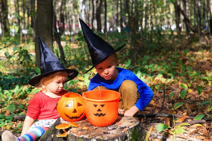 Two children in witch hats with Halloween buckets