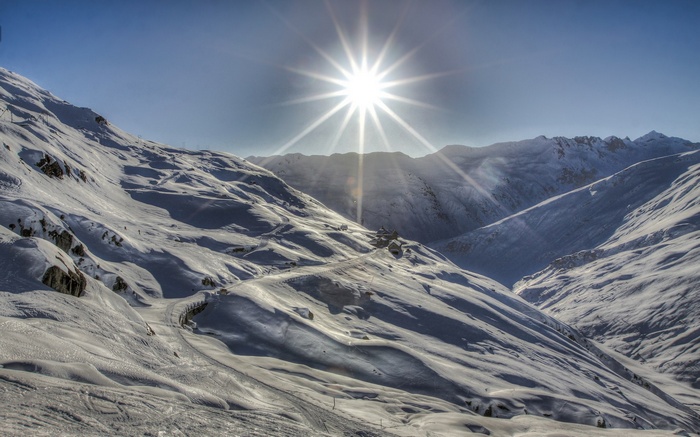 Sun shining over snow-covered mountains and ski slopes