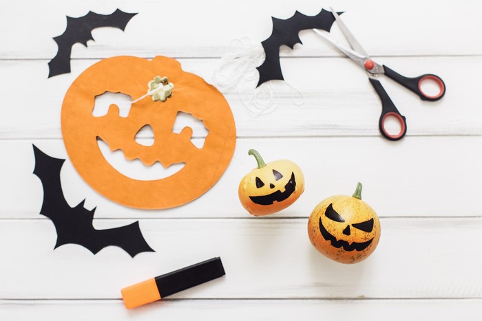 Halloween decorations: paper pumpkin, bats, mini pumpkins, scissors, and marker