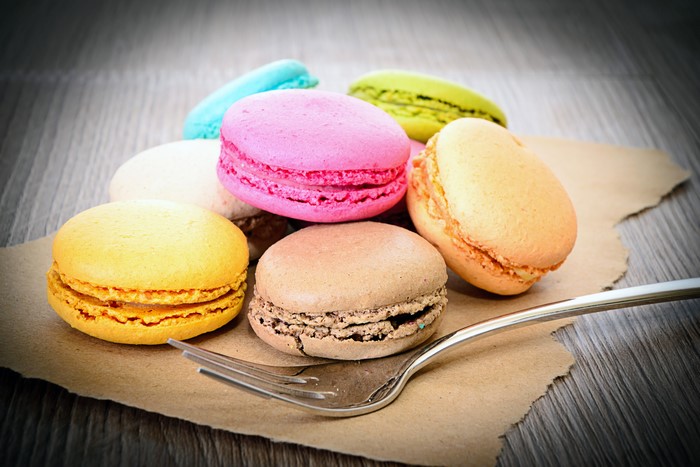 Assortment of colorful macarons on a wooden table with a fork