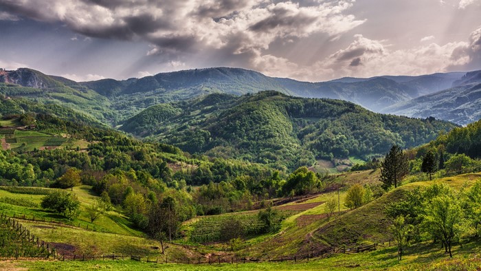 Rolling green hills and mountains under cloudy sky in Serbia