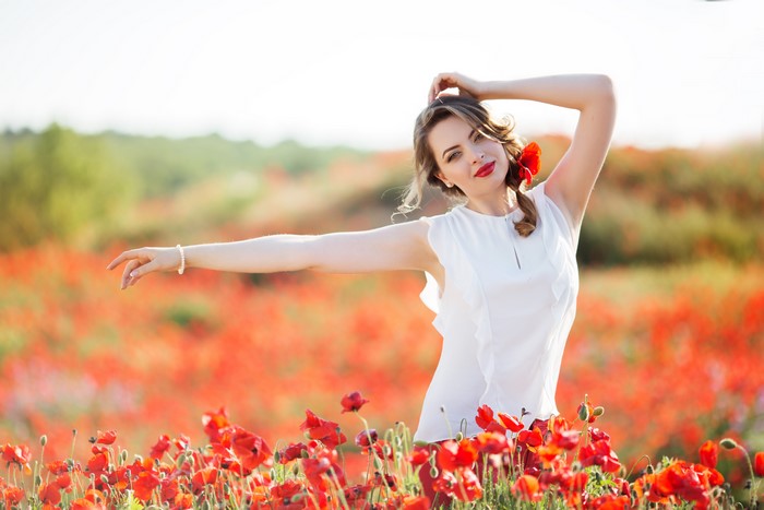 Woman in white dress in poppy field