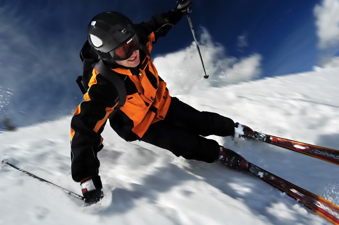 Skier in orange jacket skiing down a snowy slope