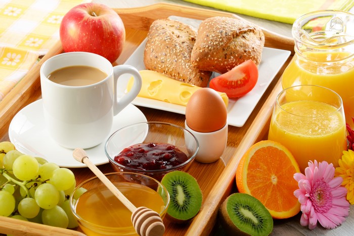 Breakfast tray with coffee, juice, fruit, and bread