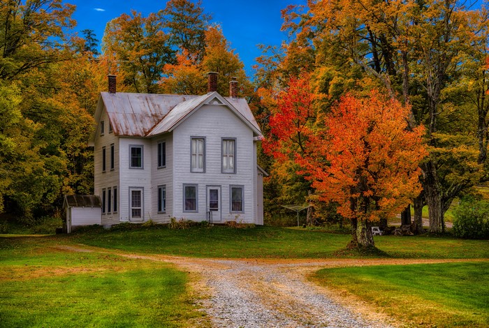 White farmhouse surrounded by autumn trees in Forestdale, USA