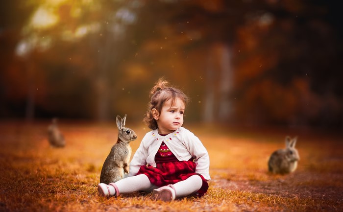 Little girl with rabbits in autumn park