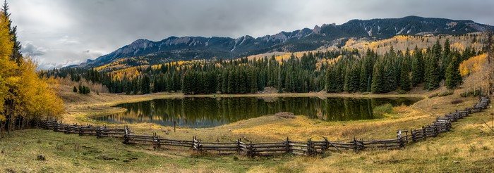 Lake and mountains in Colorado during autumn with a wooden fence