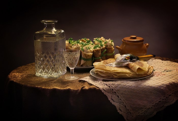 Still-life with pancakes, vodka, and appetizers