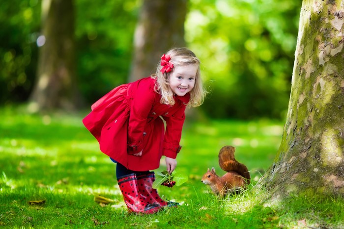 Little girl in red coat with squirrel