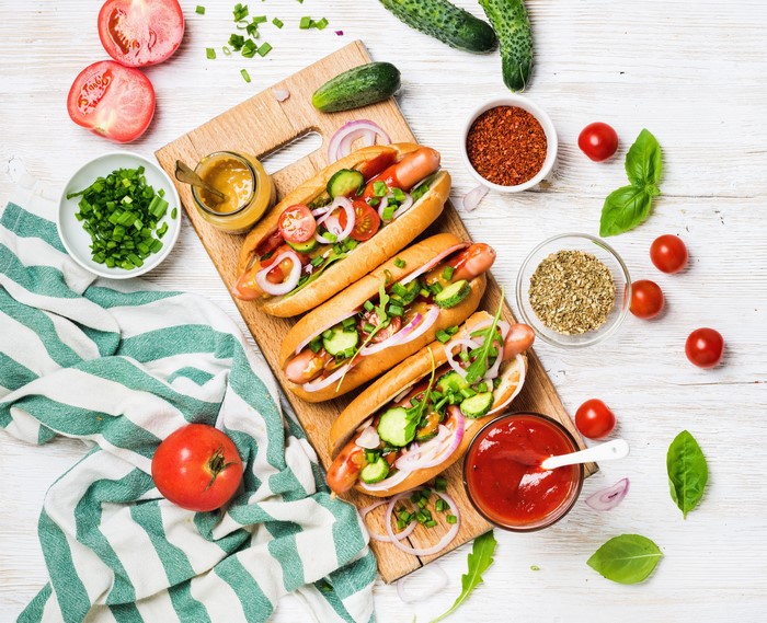 Hot dogs with vegetables and spices on a cutting board