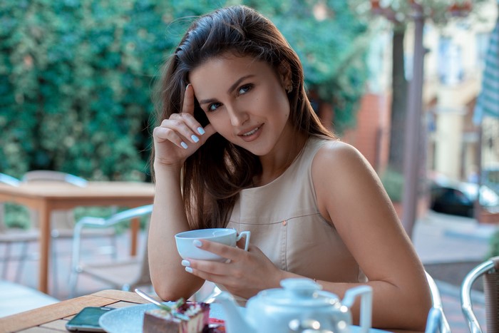Woman with brown hair holding a cup at a cafe
