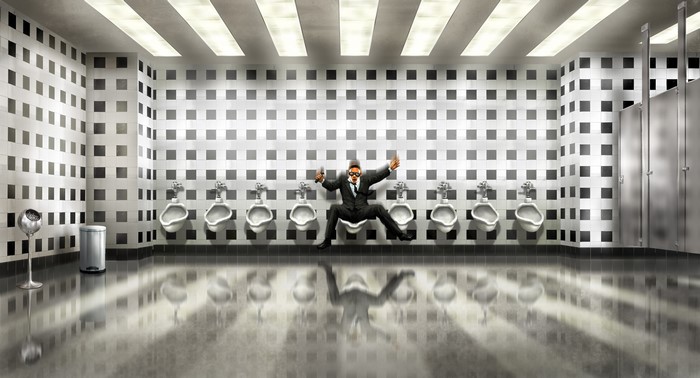 Man in suit sitting on a urinal in a bathroom