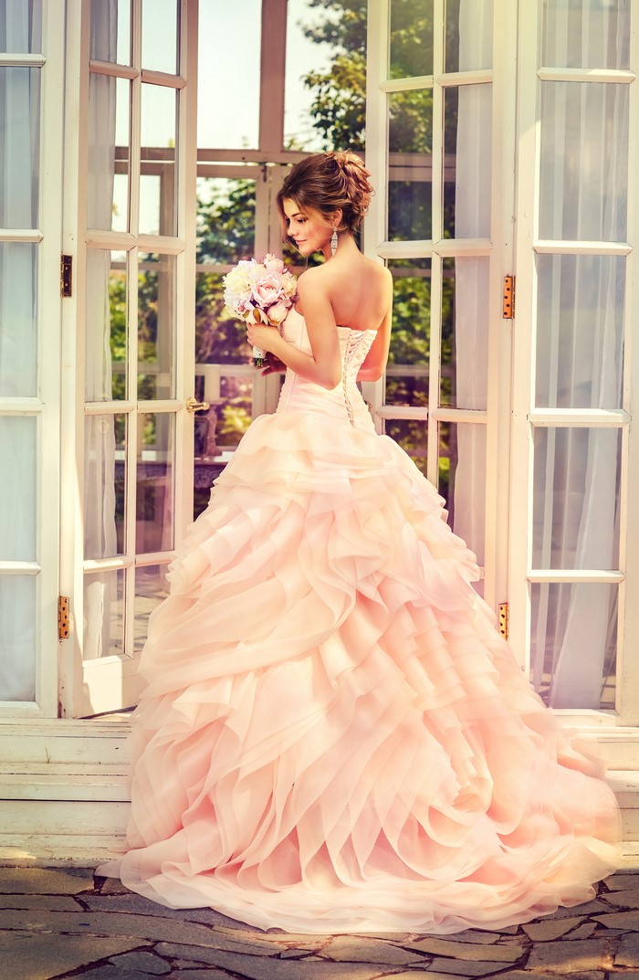 Bride in a pink ruffled dress holding a bouquet