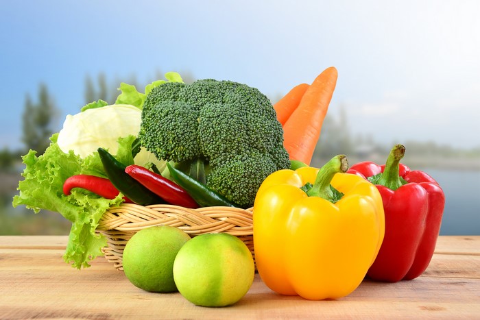 Vegetables in a wicker basket with bell peppers and limes