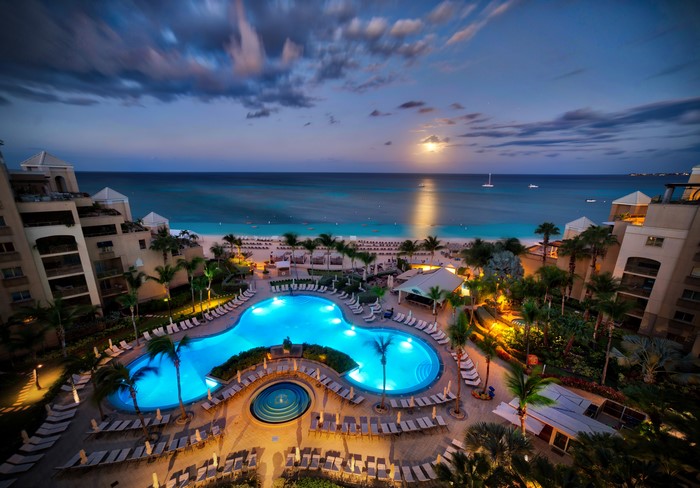 Resort pool and beach at dusk with moon