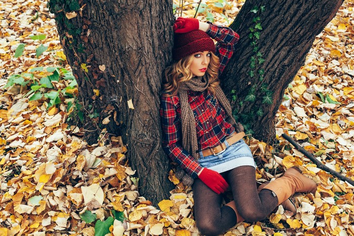 Woman in red hat and plaid shirt in autumn foliage