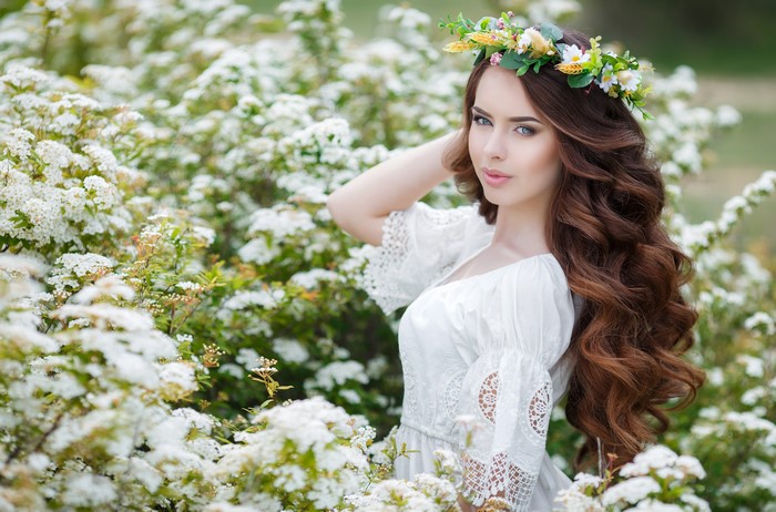 Woman with flower crown in flowering bushes
