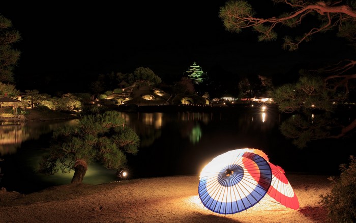 Japanese Garden at Night with Illuminated Umbrellas and Castle