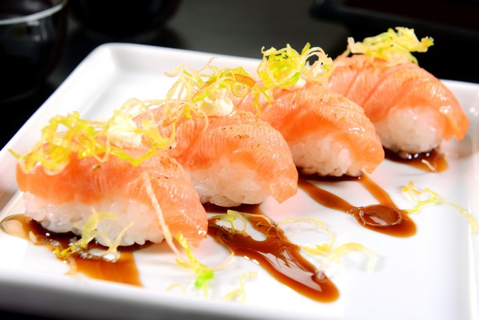 Four pieces of salmon sushi with garnish