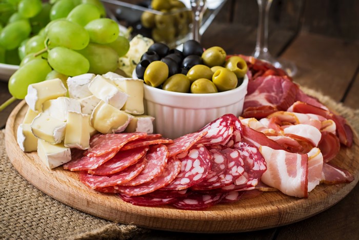Charcuterie board with cheese, meats, olives, and grapes