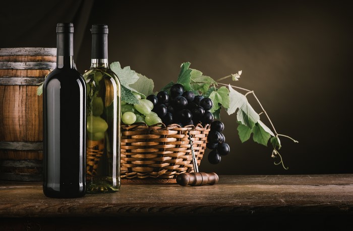 Wine bottles and grapes in a wicker basket