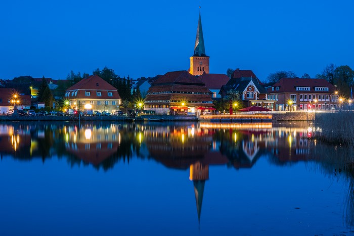 Town with church reflected in water at dusk