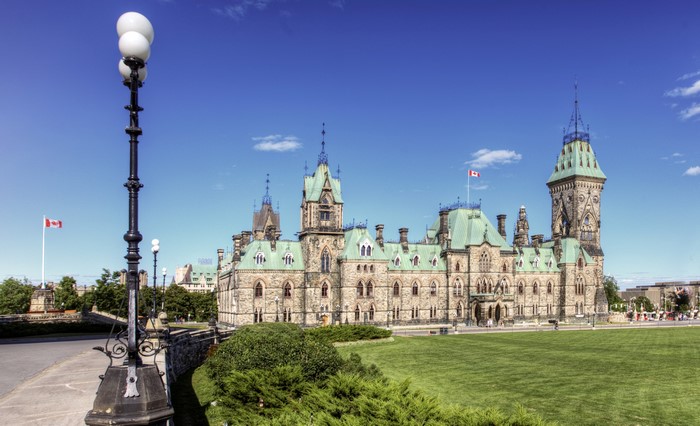 Parliament of Canada buildings with Canadian flags and street lamps