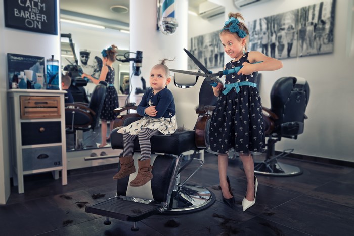 Two little girls playing barber in a salon