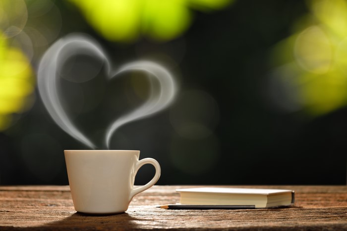 Cup of coffee with heart-shaped steam and a book