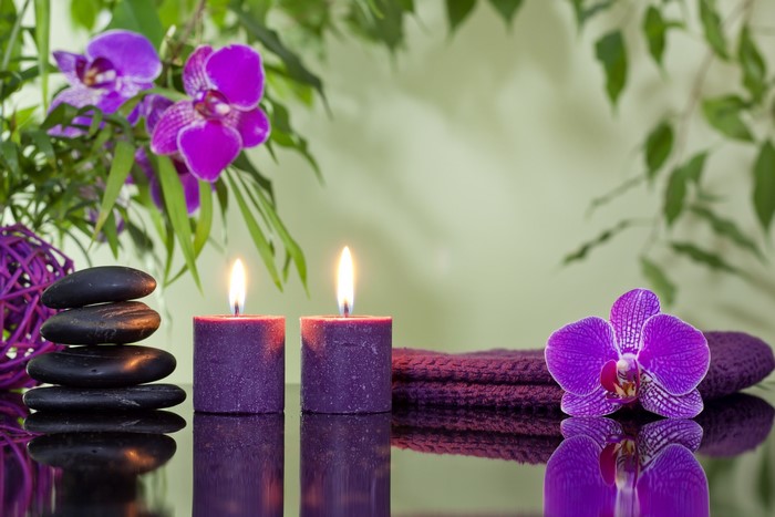 Spa setting with candles, stones, and orchids