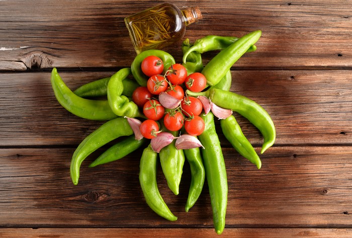 Tomatoes, Garlic, and Peppers with Olive Oil on Wood