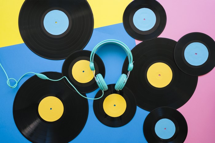 Headphones and gramophone records on colorful background