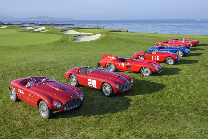 Collection of vintage red and blue Ferraris on a golf course