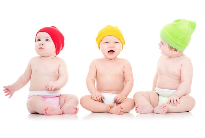 Three babies in winter hats on white background