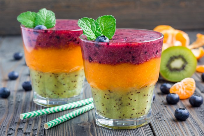 Layered fruit smoothies in highball glasses with fruit