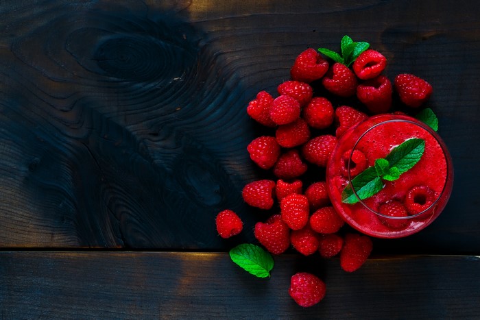 Raspberry smoothie with fresh raspberries and mint on dark wood