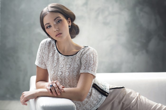 Woman with brown hair wearing a white lace top
