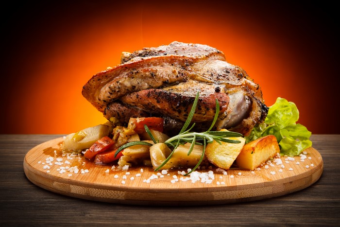 Roasted Pork Knuckle with Potatoes and Rosemary on Cutting Board