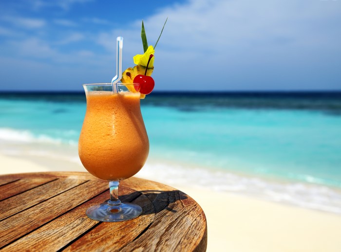 Cocktail with fruit garnish on a table by the ocean