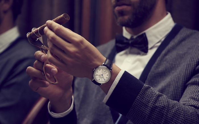 Man cutting a cigar with a watch and bow tie