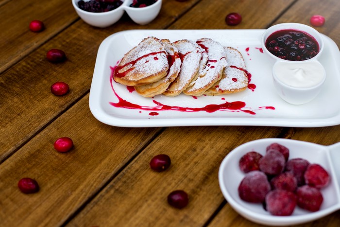 Pancakes with jam and cream on wooden planks