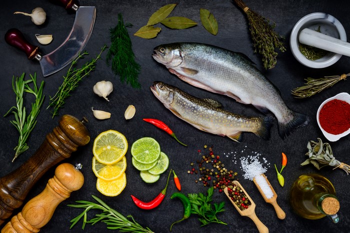 Fish, Lemons, Spices, and Herbs on Gray Background