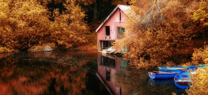 Boathouse on a lake in autumn with boats