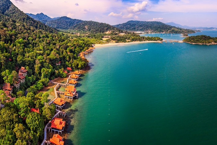 Overwater bungalows on a tropical coast with mountains and forests in Langkawi, Malaysia