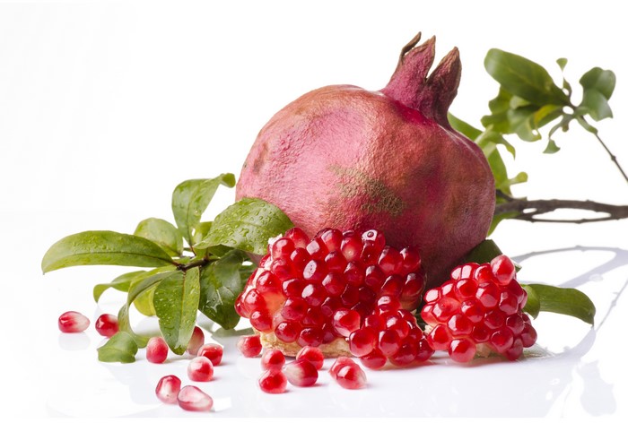 Pomegranate with leaves and seeds on white background